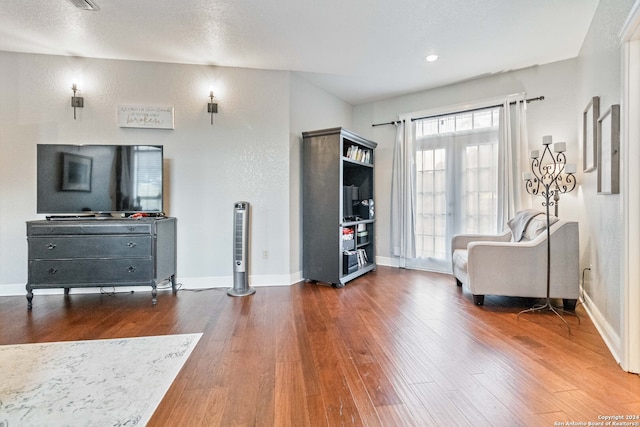 living area with french doors, a textured ceiling, and hardwood / wood-style floors