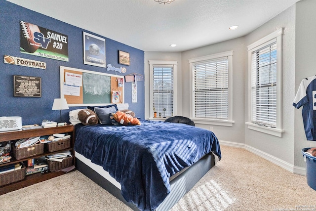 carpeted bedroom with a textured ceiling and multiple windows