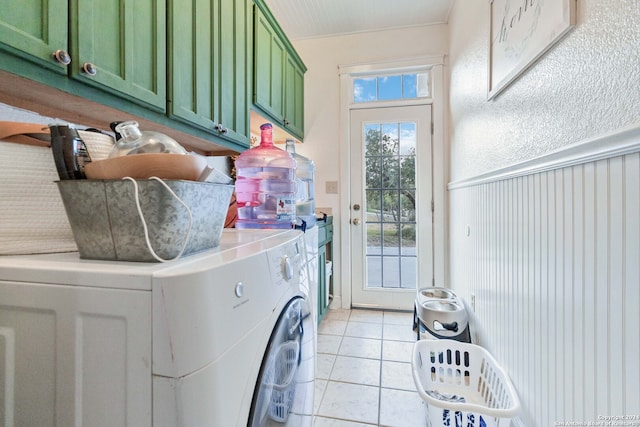 washroom featuring washing machine and dryer, cabinets, and light tile patterned flooring