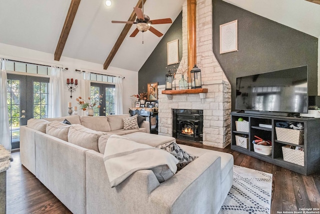 living room featuring french doors, beamed ceiling, dark wood-type flooring, and a stone fireplace