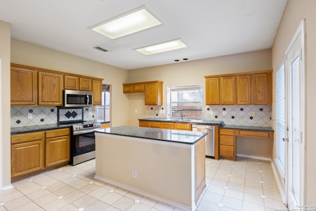 kitchen featuring light tile patterned floors, backsplash, stainless steel appliances, and a kitchen island