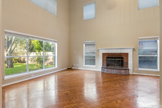 unfurnished living room featuring hardwood / wood-style floors, a fireplace, and a high ceiling