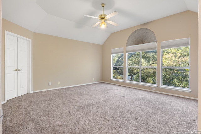 empty room with carpet floors, vaulted ceiling, plenty of natural light, and ceiling fan