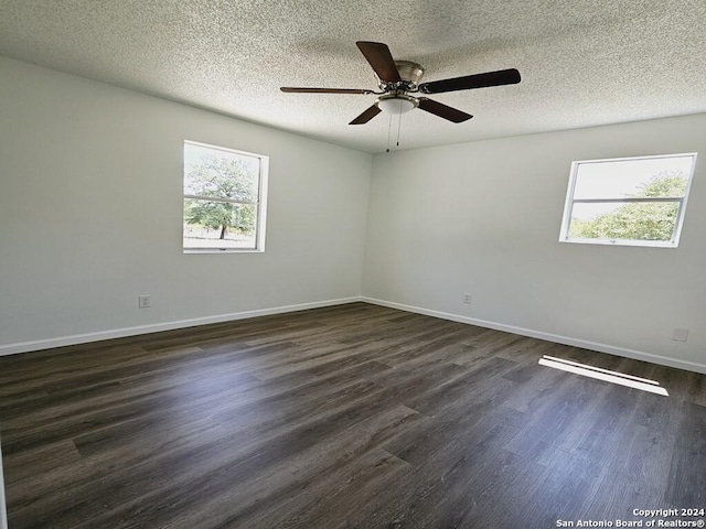 spare room with a textured ceiling, ceiling fan, dark wood-type flooring, and baseboards