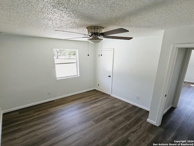 unfurnished room with dark wood-style floors, a textured ceiling, and baseboards