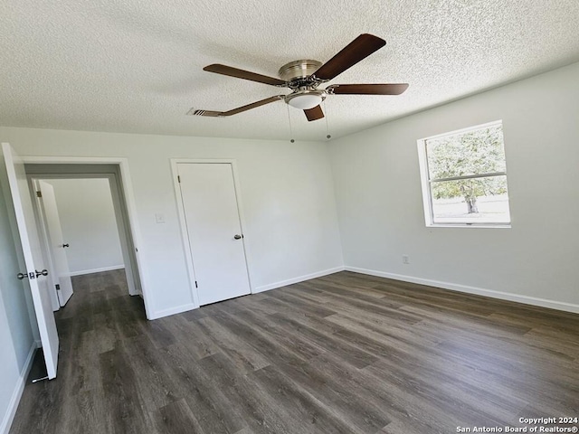 unfurnished bedroom featuring a textured ceiling, dark wood-style flooring, visible vents, and baseboards