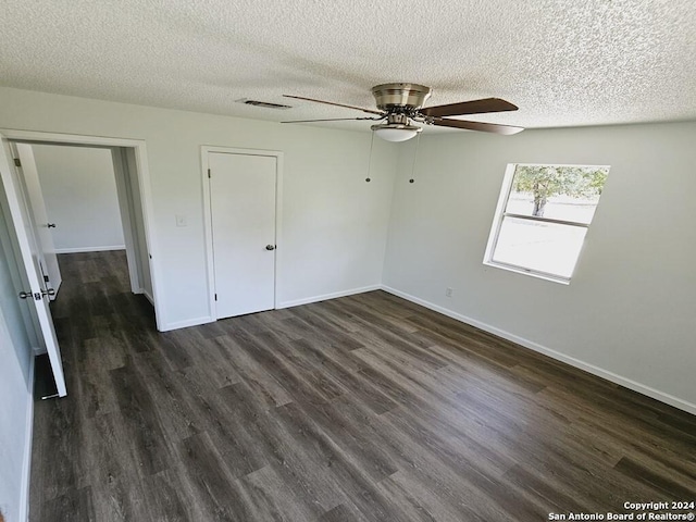 unfurnished bedroom with baseboards, visible vents, dark wood finished floors, and a textured ceiling