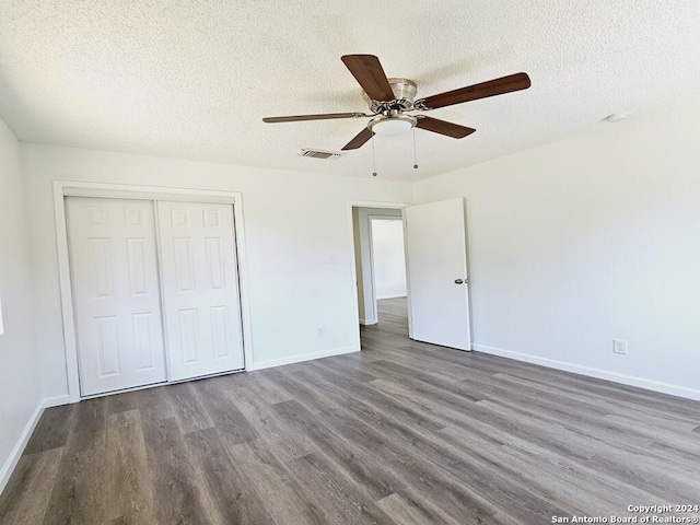 unfurnished bedroom featuring baseboards, visible vents, ceiling fan, wood finished floors, and a closet