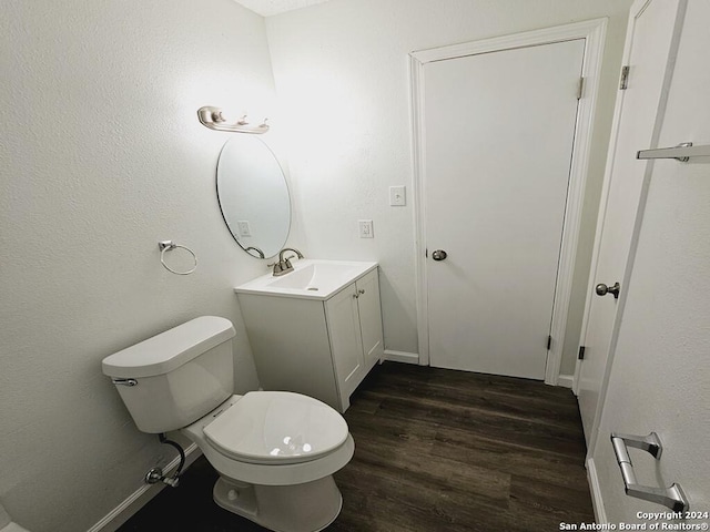 bathroom with baseboards, vanity, toilet, and wood finished floors