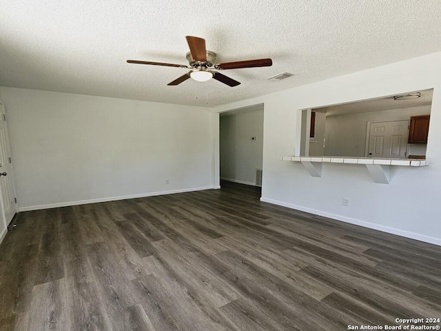 unfurnished living room with baseboards, a textured ceiling, visible vents, and dark wood-style flooring