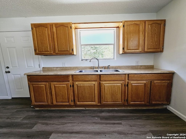 kitchen featuring dark wood-type flooring, brown cabinetry, a sink, and light countertops