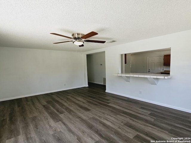 unfurnished living room featuring dark wood-style floors, visible vents, a ceiling fan, a textured ceiling, and baseboards