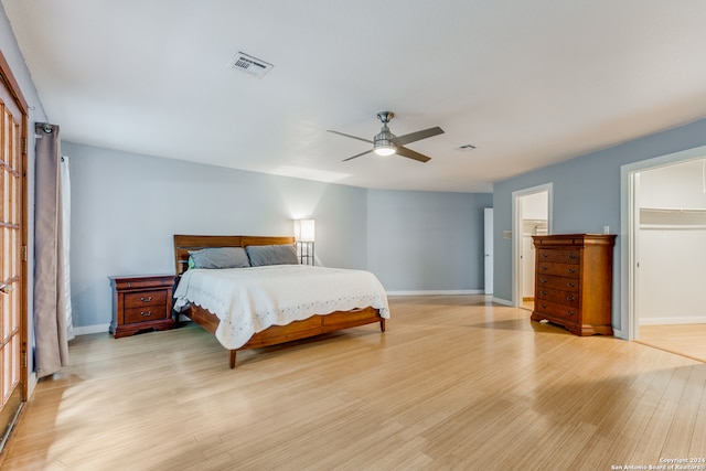 bedroom featuring light wood-type flooring, a spacious closet, and ceiling fan