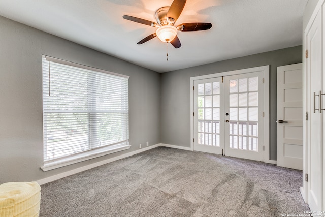 carpeted spare room featuring ceiling fan and french doors