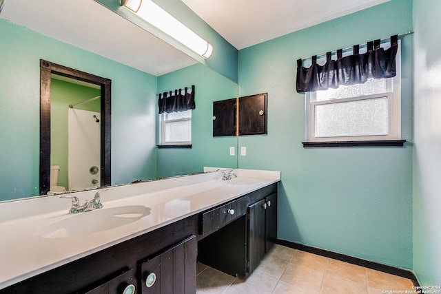 bathroom with a wealth of natural light, vanity, toilet, and tile patterned flooring