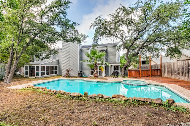 view of pool with a sunroom and an in ground hot tub