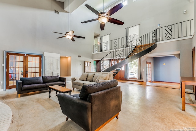 living room with a towering ceiling, ceiling fan, and french doors