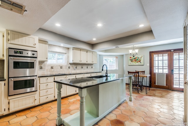 kitchen featuring a healthy amount of sunlight, a breakfast bar area, an inviting chandelier, and double oven