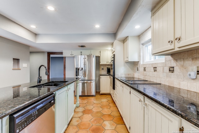 kitchen featuring stainless steel appliances, sink, dark stone counters, light tile patterned flooring, and tasteful backsplash