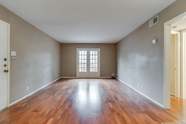 spare room featuring french doors and light hardwood / wood-style floors