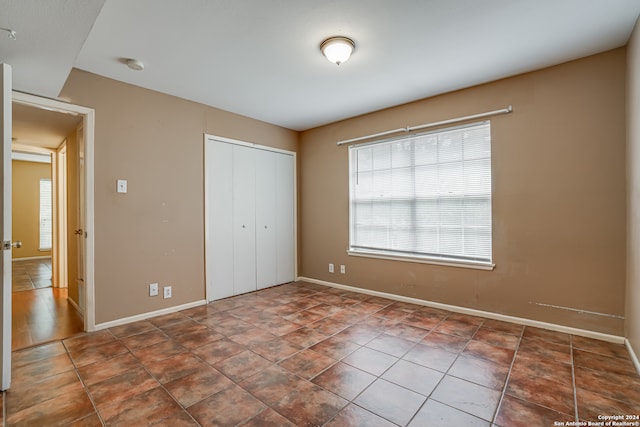 unfurnished bedroom with dark tile patterned flooring and a closet