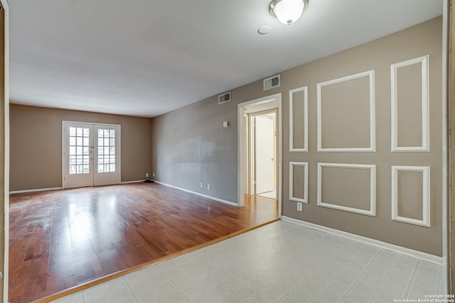 spare room featuring french doors and light hardwood / wood-style flooring