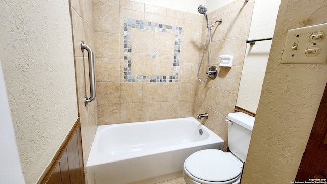 bathroom featuring toilet and tiled shower / bath