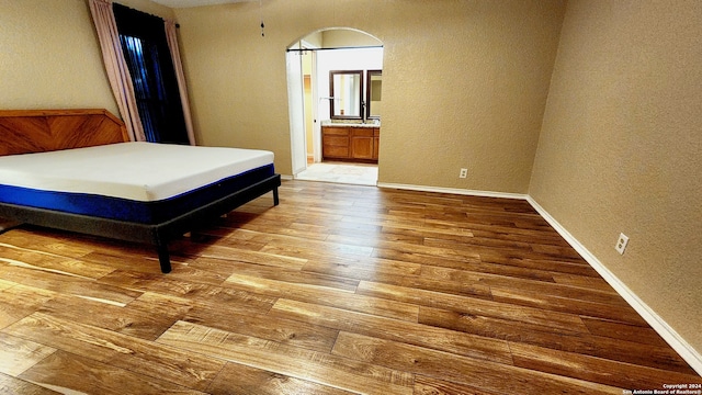 bedroom featuring connected bathroom and light hardwood / wood-style floors