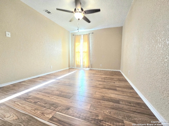 unfurnished room with visible vents, a textured wall, baseboards, and hardwood / wood-style flooring