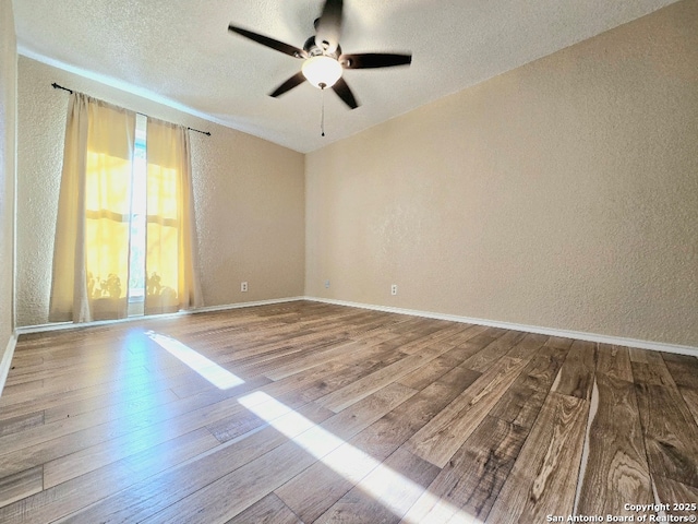 unfurnished room featuring a textured wall, ceiling fan, a textured ceiling, wood finished floors, and baseboards