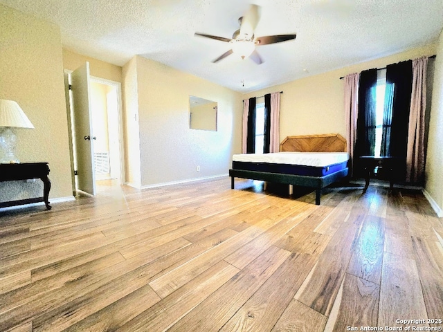 bedroom featuring a textured ceiling, wood-type flooring, a ceiling fan, and baseboards