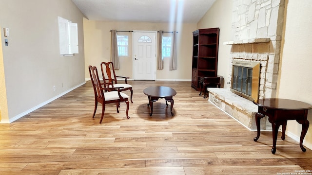 living area featuring a textured ceiling, light wood-type flooring, and a fireplace