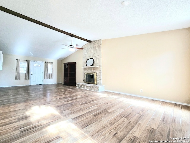 unfurnished living room with a stone fireplace, ceiling fan, a textured ceiling, and wood finished floors