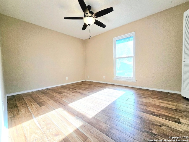 unfurnished room featuring ceiling fan, wood finished floors, and baseboards