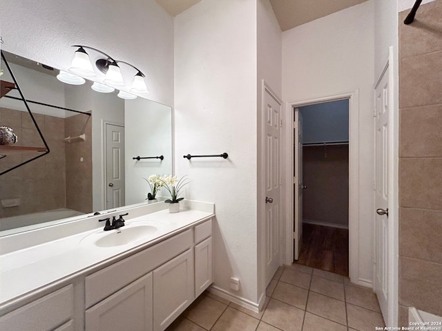 bathroom with tile patterned flooring, vanity, and tiled shower / bath