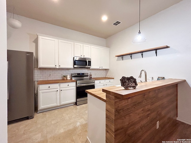 kitchen featuring wooden counters, stainless steel appliances, white cabinetry, and decorative backsplash