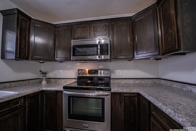 kitchen with stainless steel appliances, light stone countertops, and dark brown cabinets