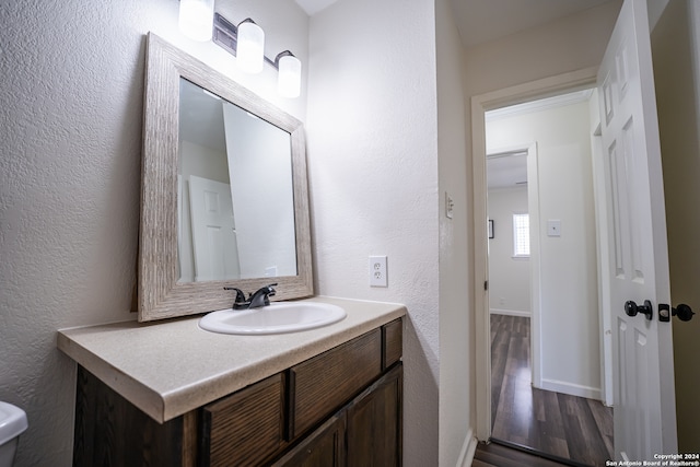 bathroom with vanity, toilet, and hardwood / wood-style floors