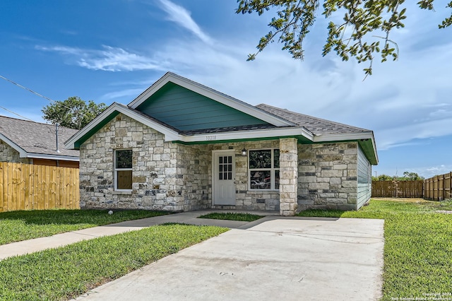 view of front of house with stone siding, fence, and a front lawn