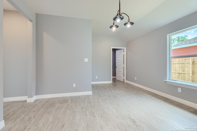 empty room featuring baseboards and vaulted ceiling