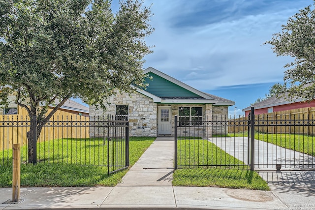 view of front of house with stone siding, a fenced front yard, a gate, and a front lawn