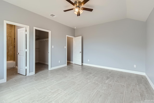 unfurnished bedroom with ceiling fan, visible vents, baseboards, vaulted ceiling, and a walk in closet