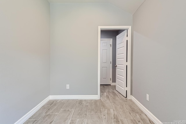 empty room featuring lofted ceiling and baseboards