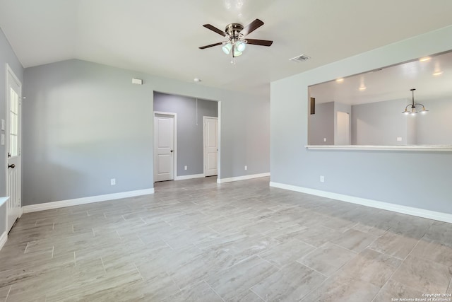 empty room featuring baseboards, visible vents, vaulted ceiling, and ceiling fan with notable chandelier