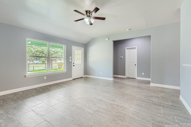 spare room with a ceiling fan, vaulted ceiling, and baseboards