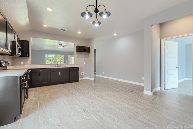 kitchen with light countertops, stainless steel microwave, visible vents, a sink, and ceiling fan with notable chandelier