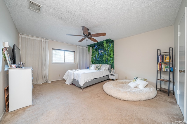 bedroom featuring light carpet, a textured ceiling, and ceiling fan