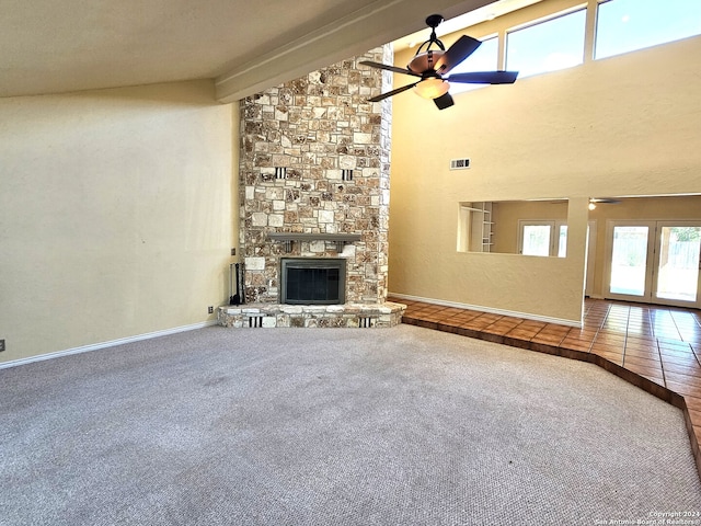 unfurnished living room featuring ceiling fan, carpet, beam ceiling, and a fireplace