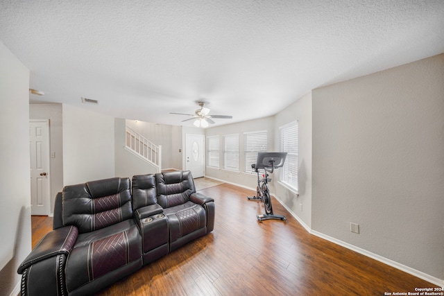 living room with a textured ceiling, wood-type flooring, and ceiling fan