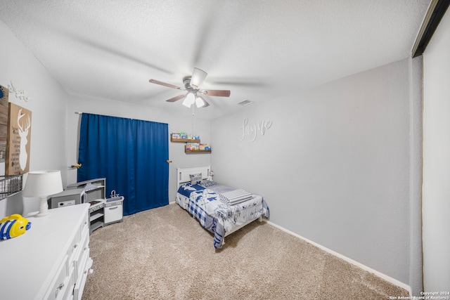 bedroom with ceiling fan, light carpet, and a textured ceiling